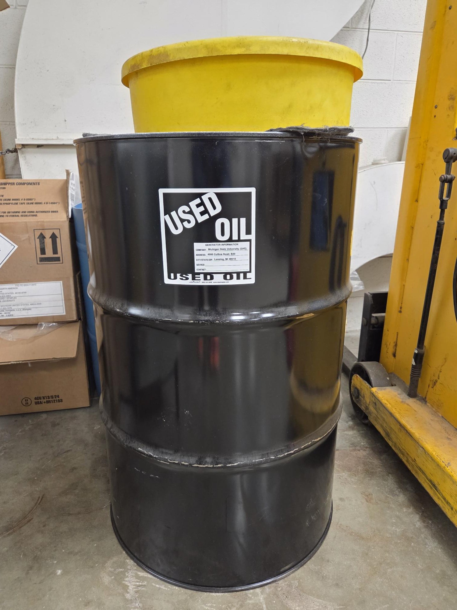 55-gallon metal drum with EHS provided Used Oil label on side.